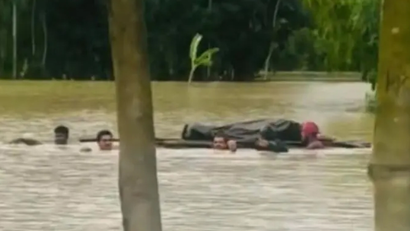 বন্যার পানিতে ডুবে আছে এলাকা, ভেলায় ভাসিয়ে লাশ নেওয়া হলো দূরের কবরস্থানে